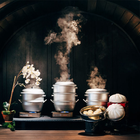 Steamers steaming bao next to a buque of flowers and large bao shaped baskets on a stand